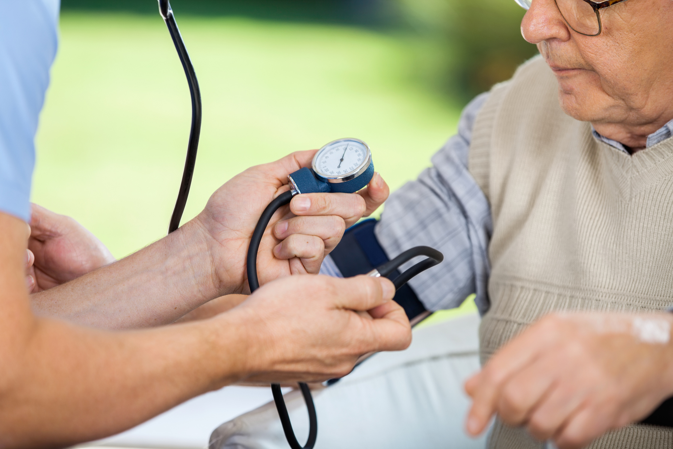 Male Caretaker Measuring Blood Pressure of Elderly Man